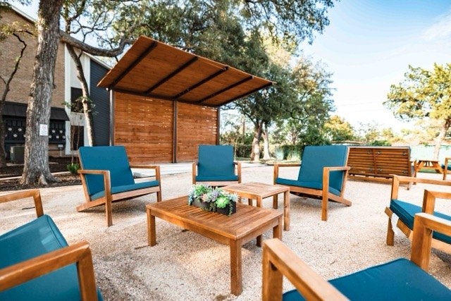 Outdoor lounge with teal chairs and a cedar privacy wall
